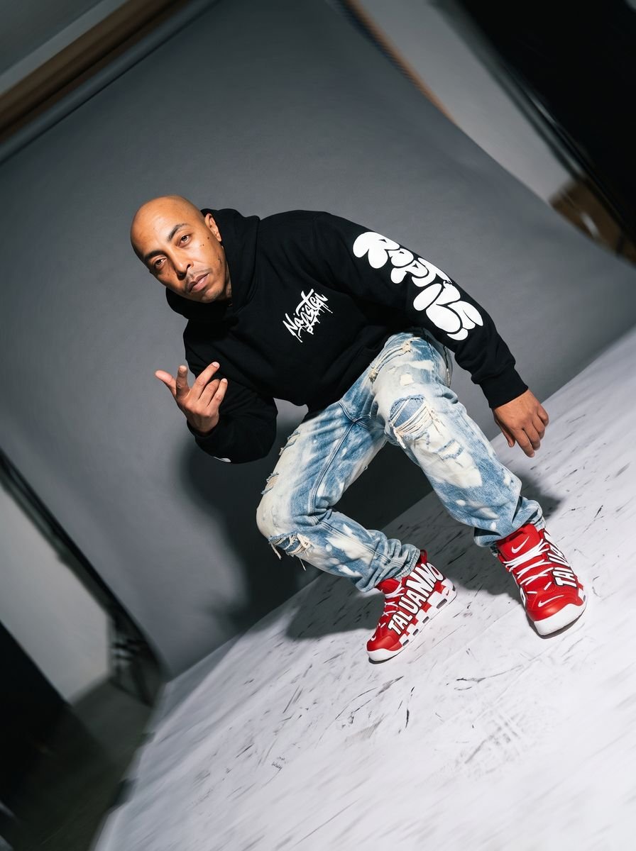 Fisheye studio shot of a man in a black hoodie and bleached jeans
