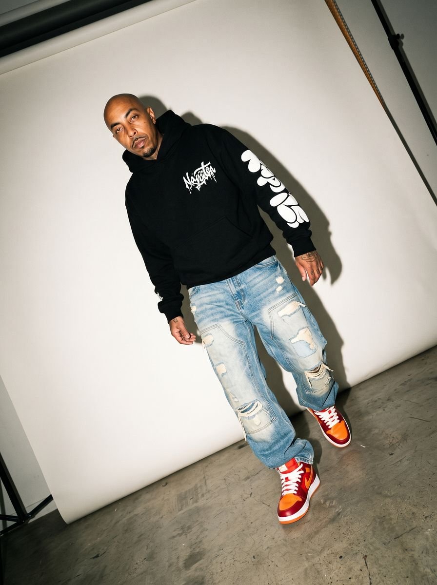 Man leaning back in a black hoodie and light-wash distressed jeans