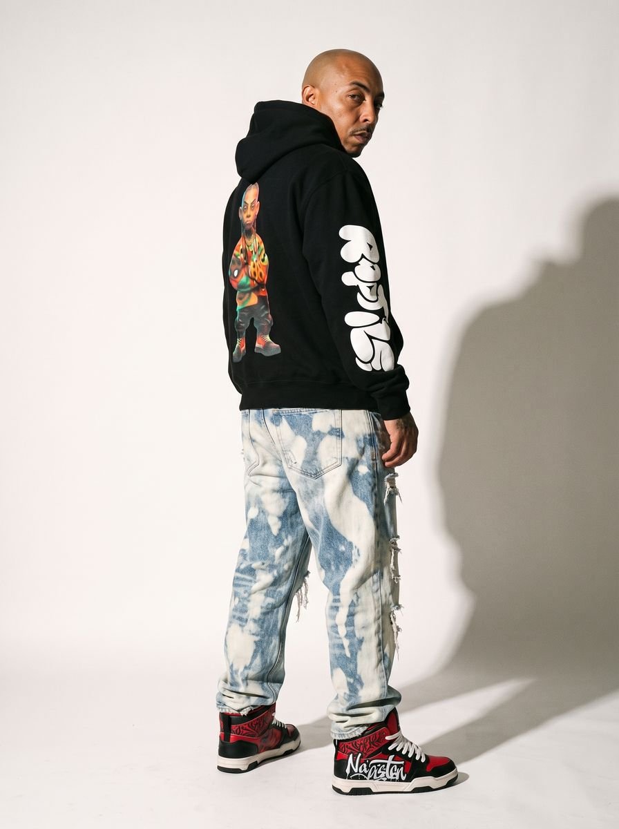 Man in an oversized black hoodie standing against a grey wall