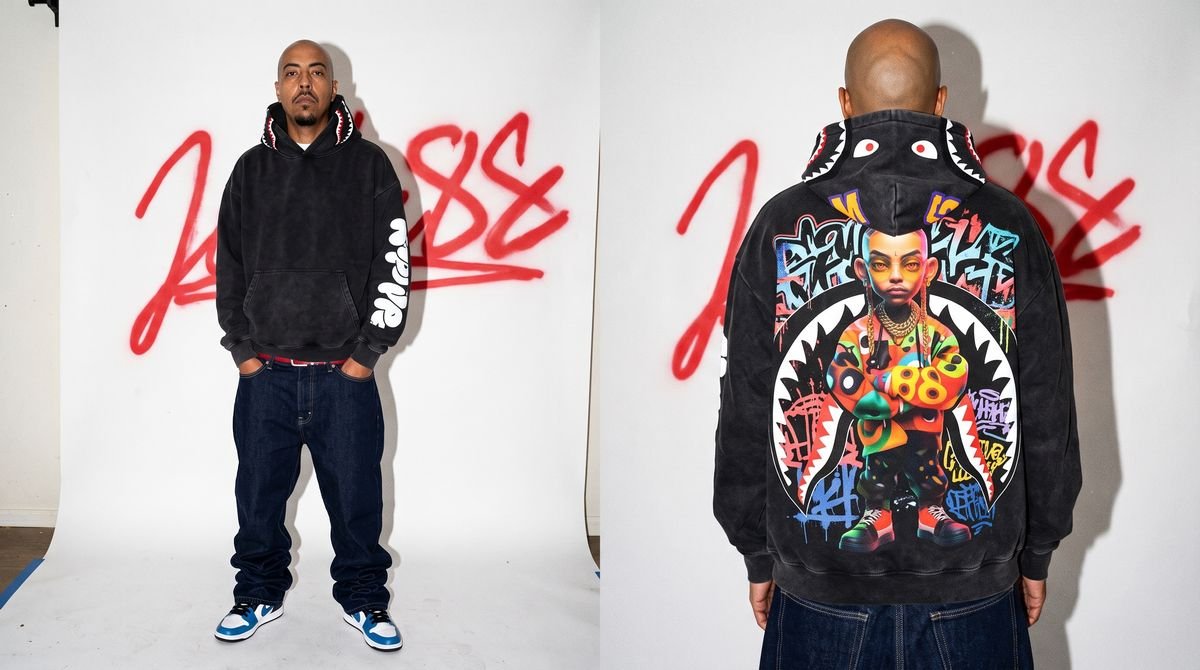 Man turned away showing a black hoodie with a colorful back print, wide jeans